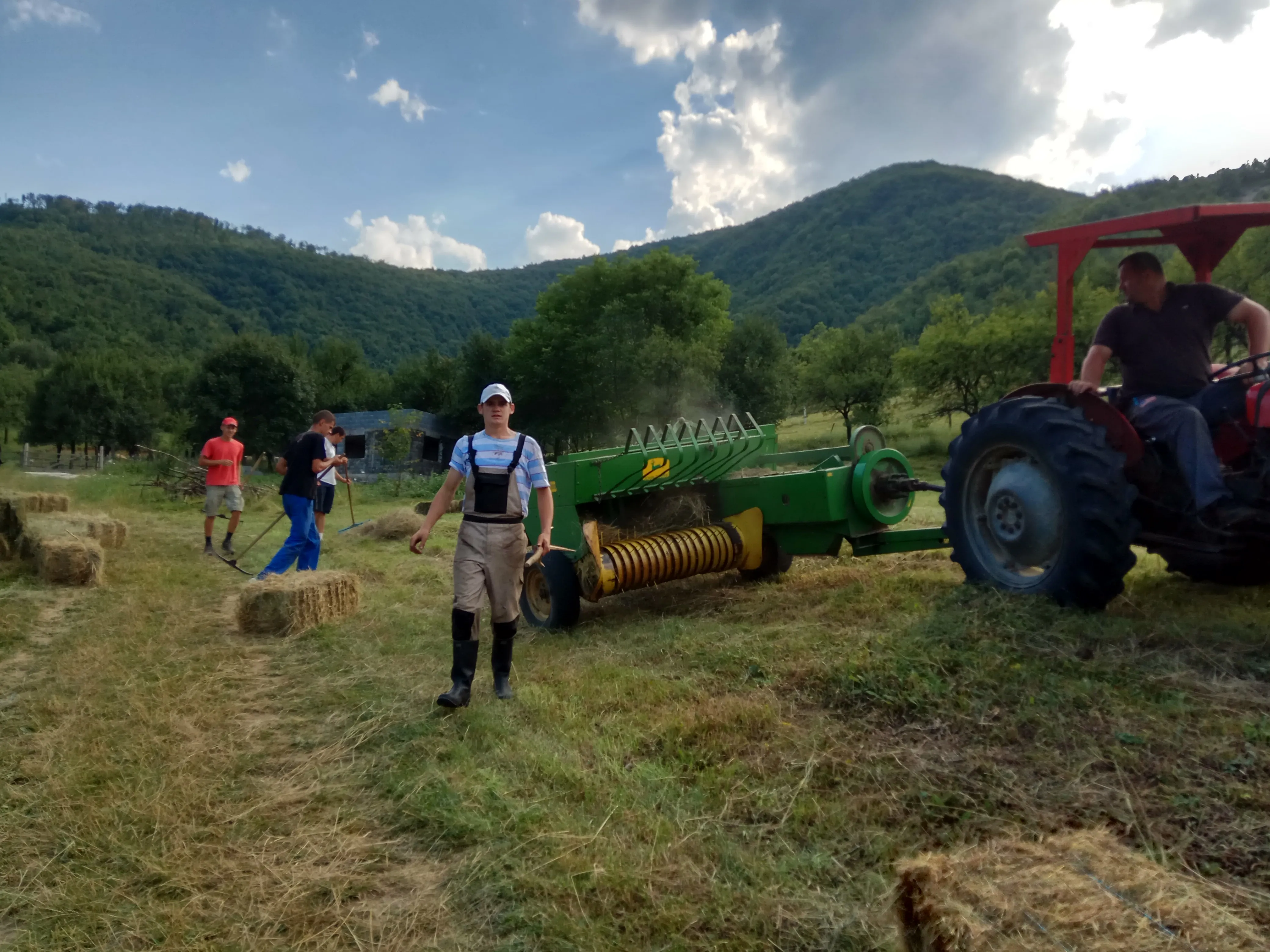 Young people making hay with a tractor in the Bosnian hills at Grace Valley